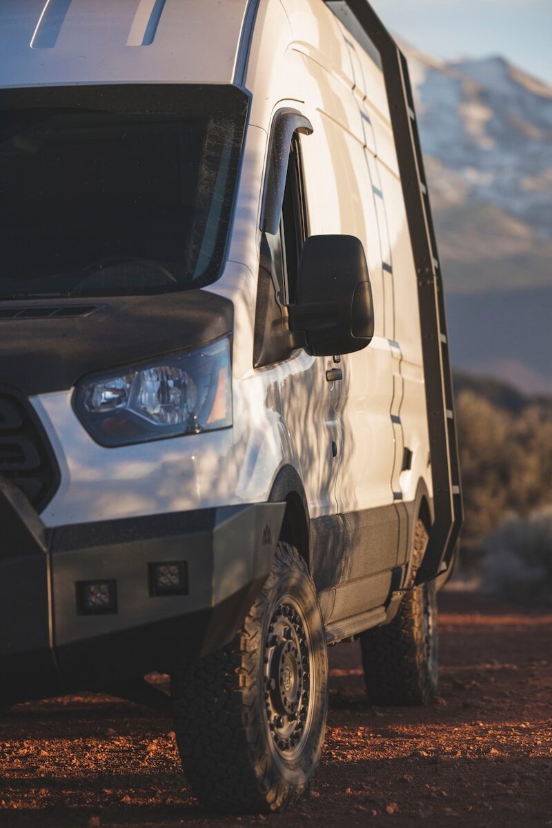 a van parked on a dirt road with mountains in the background